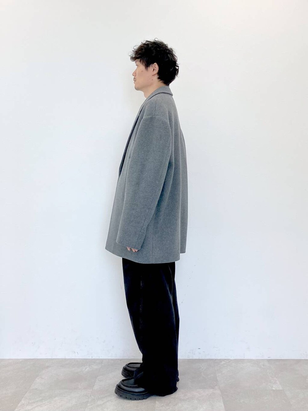 グレー系のステンカラーコート、ブラック系のデニムパンツ、ブラック系のデニムパンツを着用したメンズの秋コーディネートの6枚目の写真