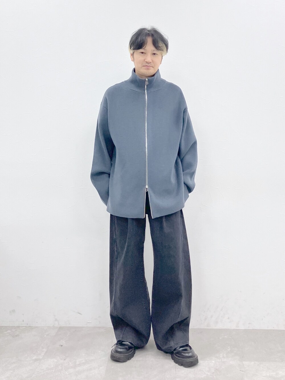 ブラック系のダウンジャケット/コート、グレー系のカーディガン/ボレロ、ブラック系のデニムパンツを着用したメンズの秋コーディネートの9枚目の写真