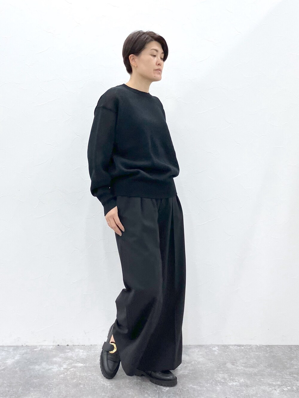 ブラック系のニット/セーター、ブラック系のスラックスを着用したレディースの春コーディネートの5枚目の写真