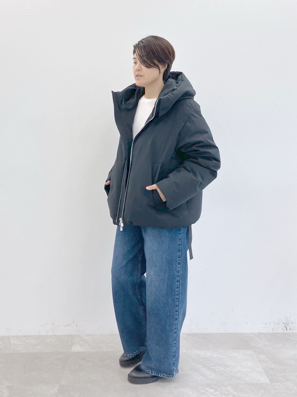 ブラック系のダウンジャケット/コート、ホワイト系のTシャツ/カットソー、ブルー系のデニムパンツを着用したレディースの秋コーディネートの2枚目の写真