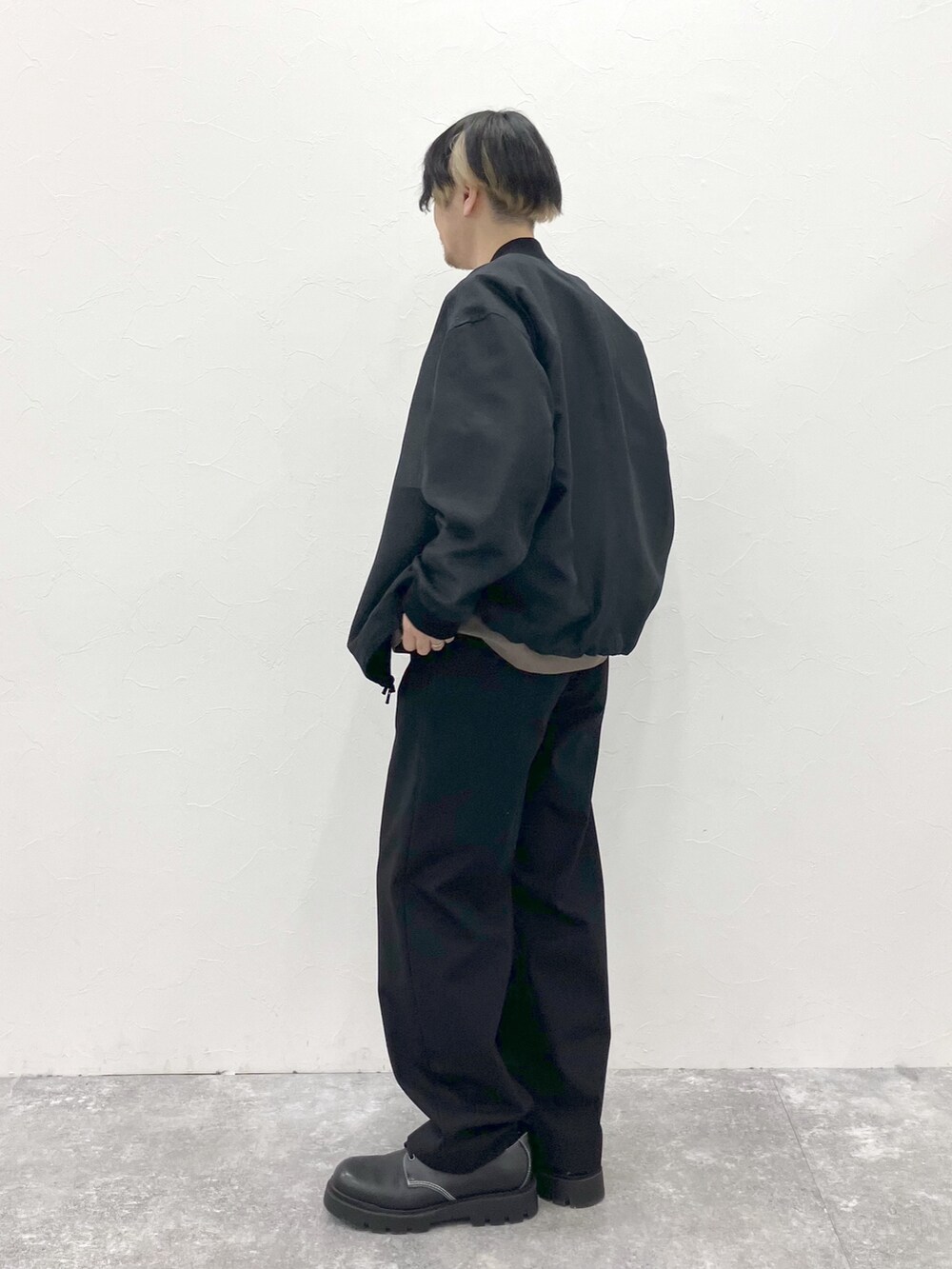 ブラック系のMA-1、ブラウン系のTシャツ/カットソー、ブラック系のスラックスを着用したメンズの春コーディネートの6枚目の写真