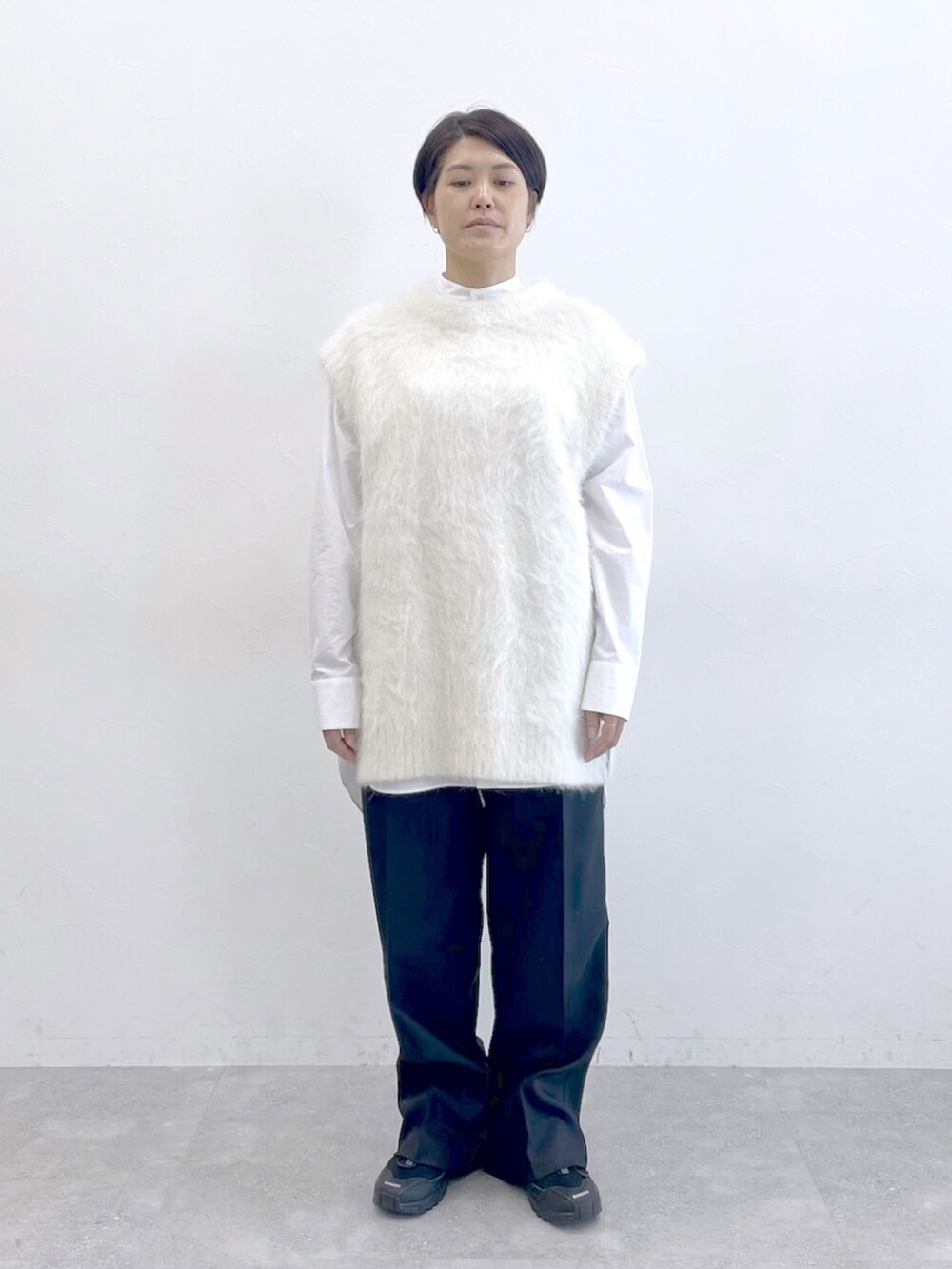 ホワイト系のニット/セーター、ホワイト系のシャツ/ブラウス、ブラック系のスラックスを着用したレディースの冬コーディネートの6枚目の写真