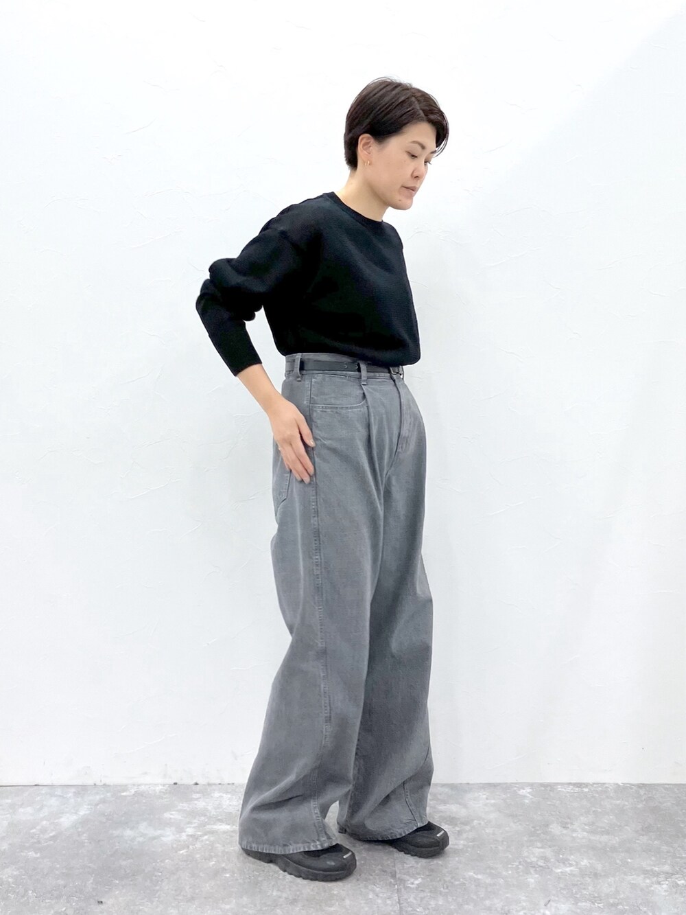 ブラック系のニット/セーター、グレー系のデニムパンツを着用したレディースの春コーディネートの2枚目の写真