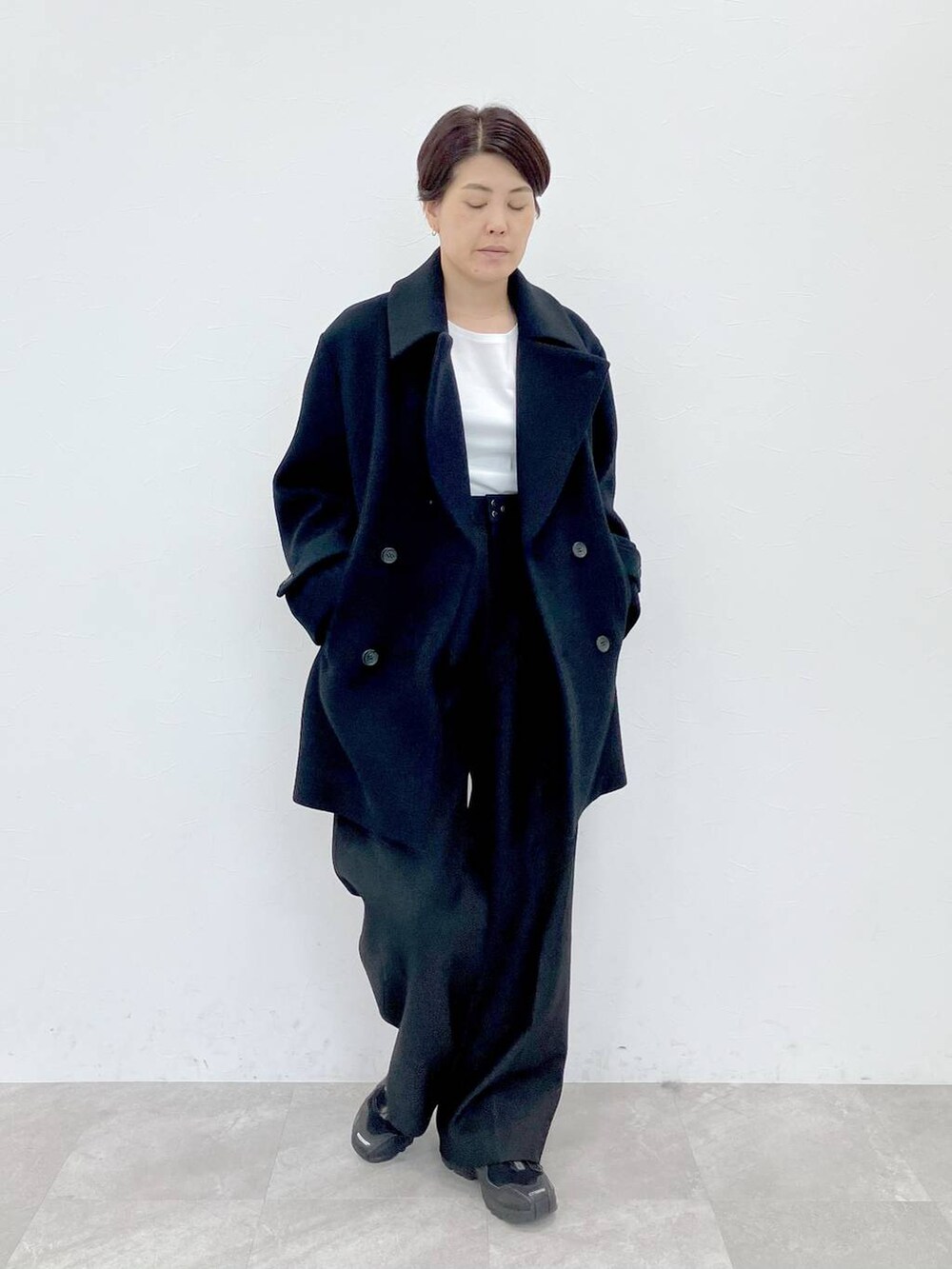 ブラック系のピーコート、ホワイト系のTシャツ/カットソー、ブラック系のサロペット/オーバーオールを着用したレディースの秋コーディネートの2枚目の写真