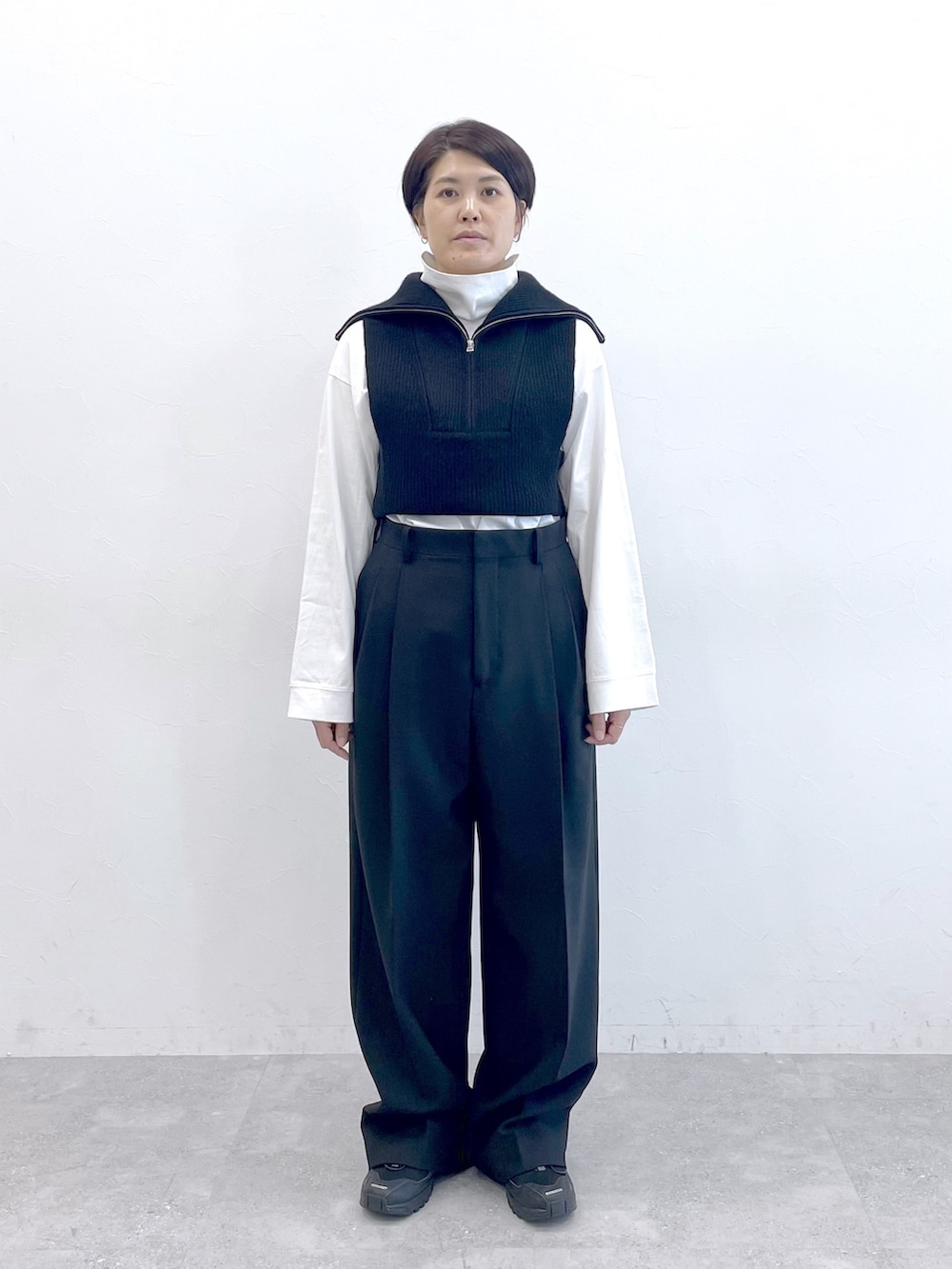ブラック系のベスト、ホワイト系のTシャツ/カットソー、ブラック系のスラックスを着用したレディースの冬コーディネートの5枚目の写真