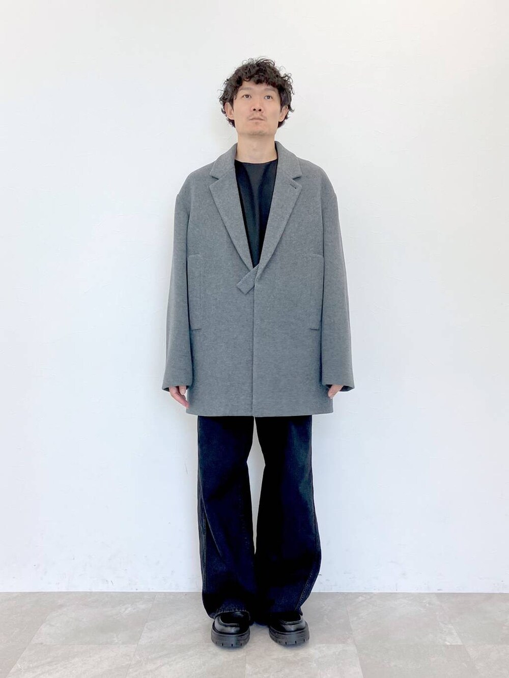 グレー系のステンカラーコート、ブラック系のデニムパンツ、ブラック系のデニムパンツを着用したメンズの秋コーディネートの5枚目の写真