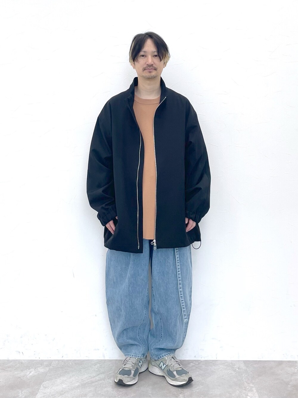 ブラック系のブルゾン、ベージュ系のトップス、ブルー系のデニムパンツを着用したメンズの冬コーディネートの6枚目の写真