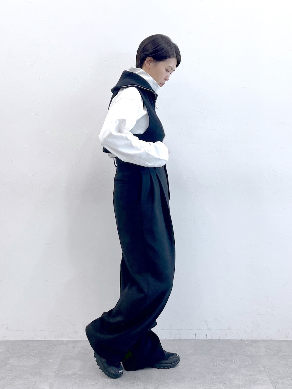 ブラック系のベスト、ホワイト系のTシャツ/カットソー、ブラック系のスラックスを着用したレディースの冬コーディネートの3枚目の写真
