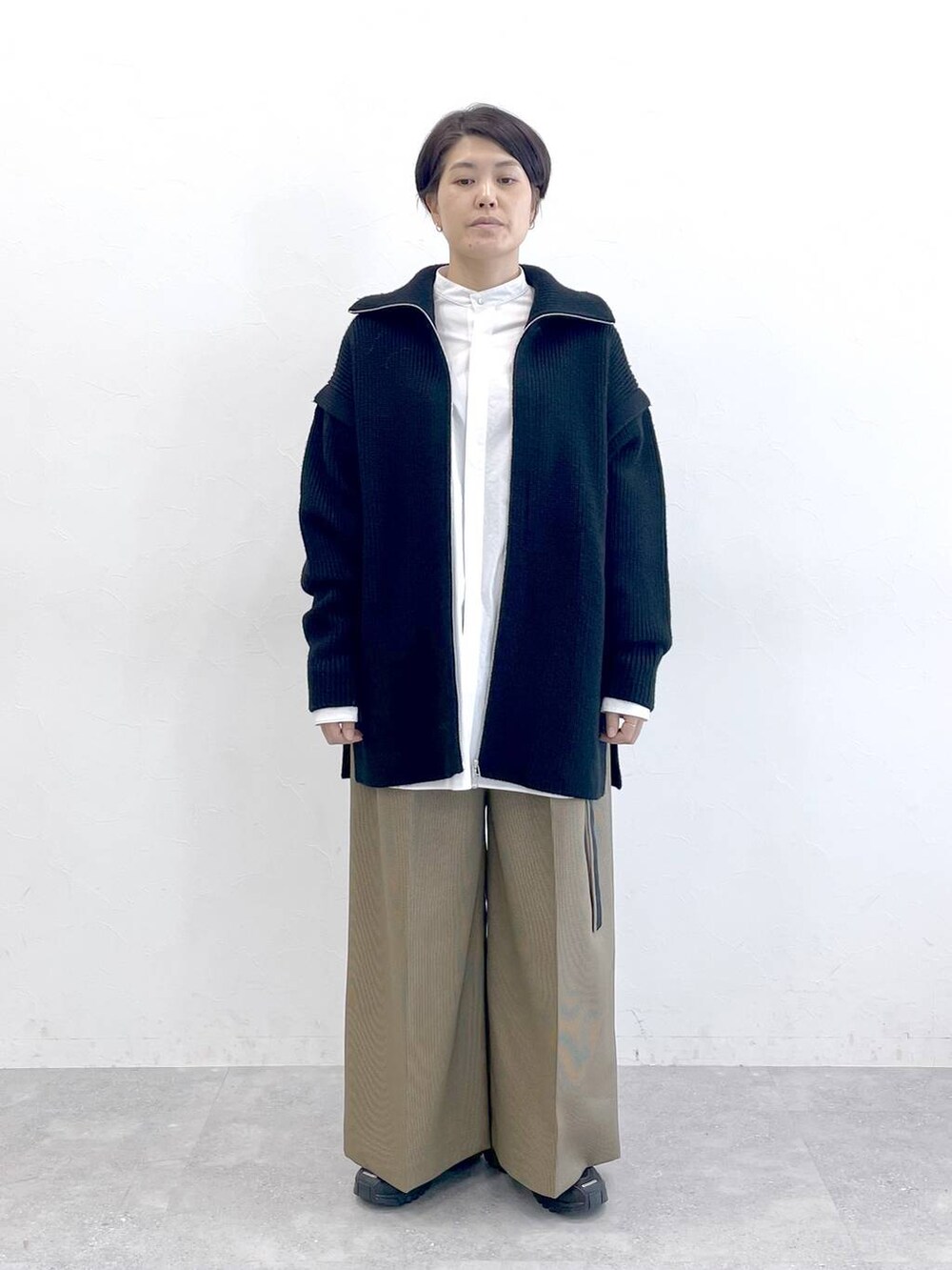ホワイト系のシャツ/ブラウス、ベージュ系のスラックス、ブラック系のニット/セーターを着用したレディースの秋コーディネートの5枚目の写真