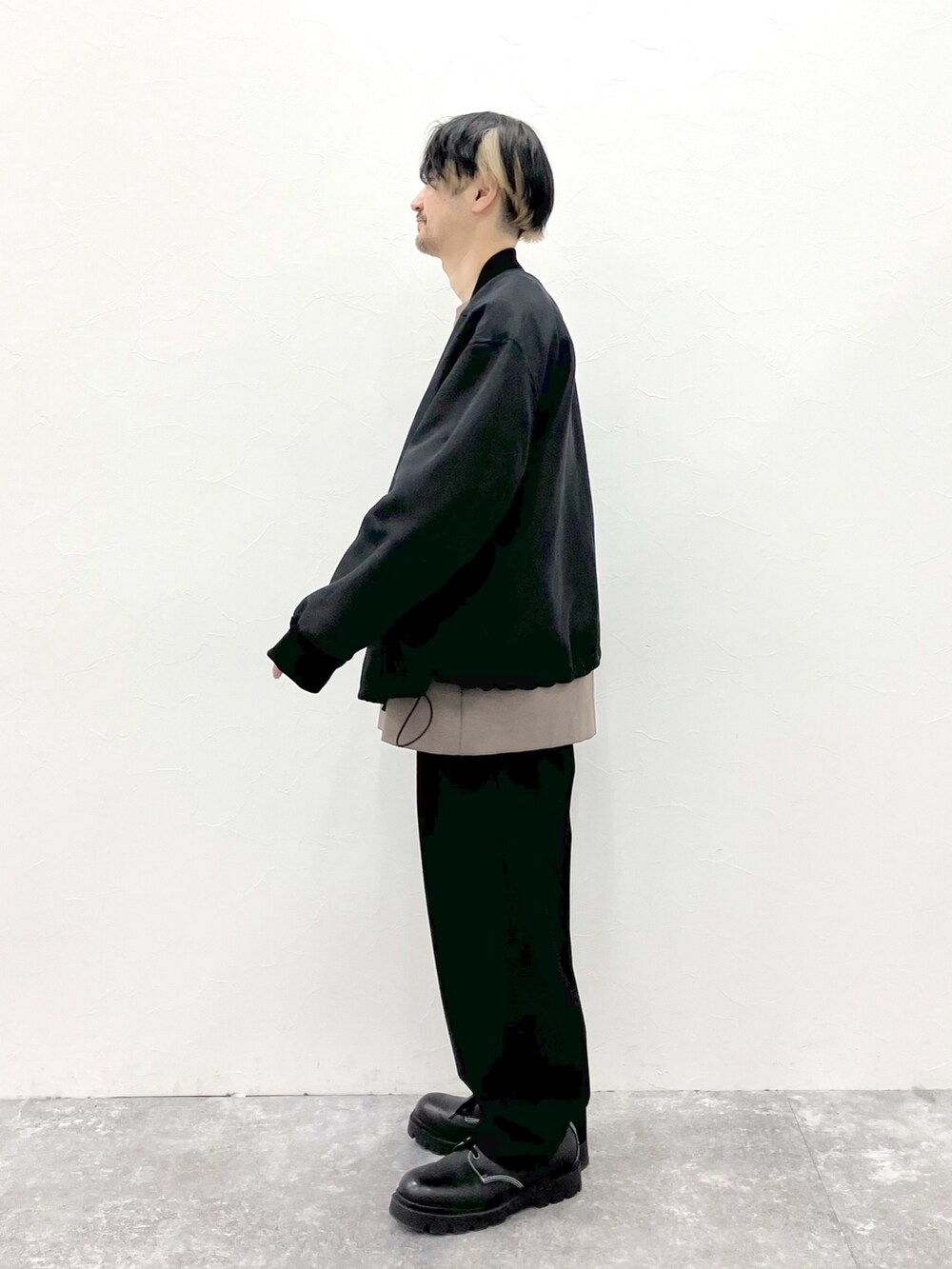ブラック系のMA-1、ブラウン系のTシャツ/カットソー、ブラック系のスラックスを着用したメンズの春コーディネートの8枚目の写真