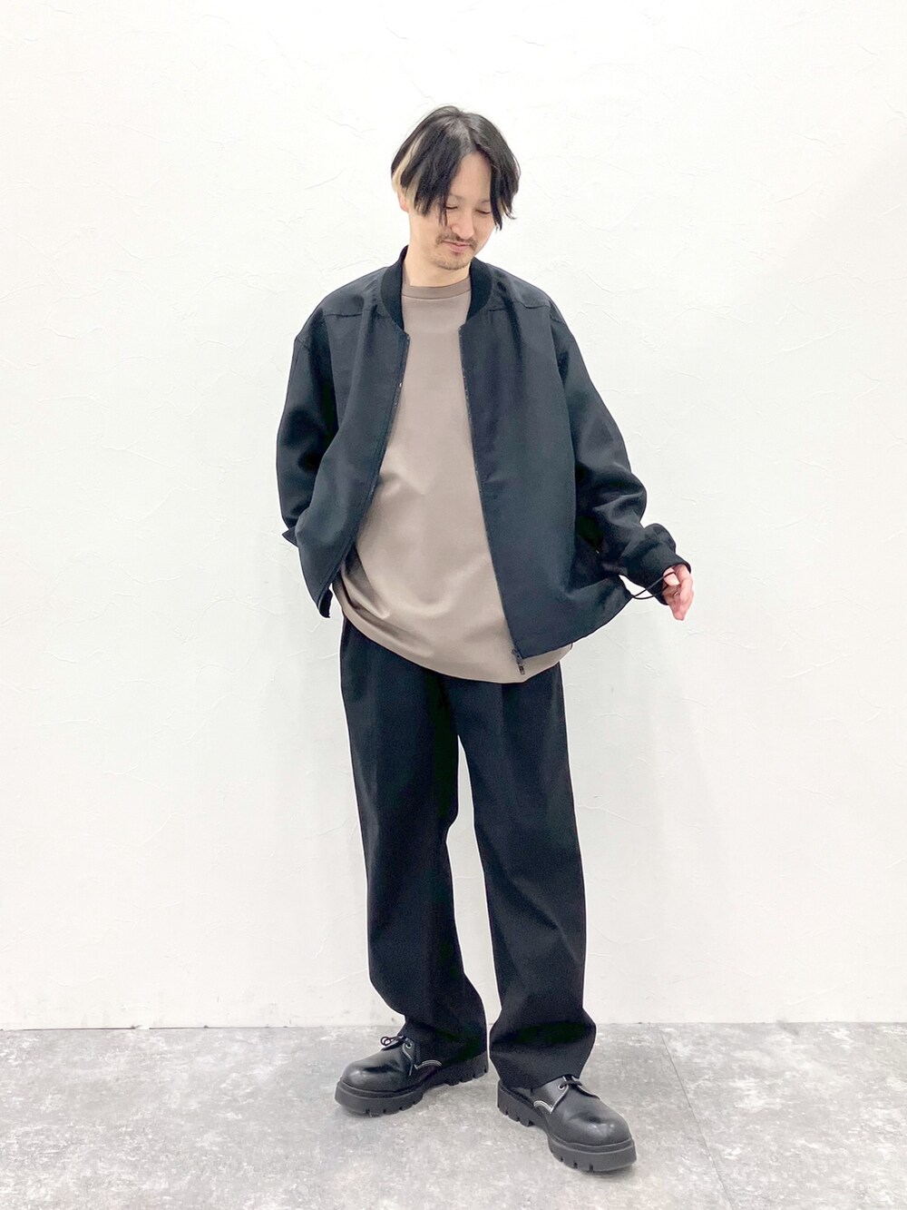ブラック系のMA-1、ブラウン系のTシャツ/カットソー、ブラック系のスラックスを着用したメンズの春コーディネートの4枚目の写真