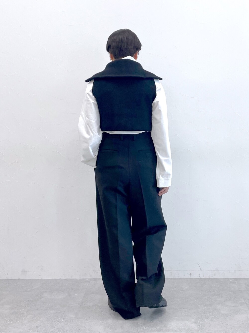 ブラック系のベスト、ホワイト系のTシャツ/カットソー、ブラック系のスラックスを着用したレディースの冬コーディネートの4枚目の写真