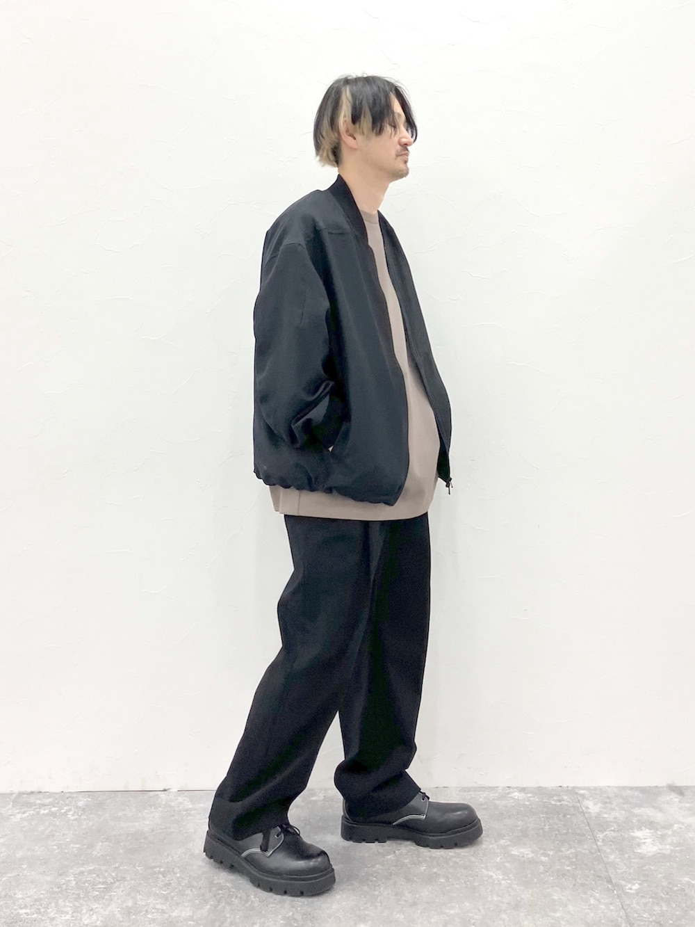 ブラック系のMA-1、ブラウン系のTシャツ/カットソー、ブラック系のスラックスを着用したメンズの春コーディネートの2枚目の写真