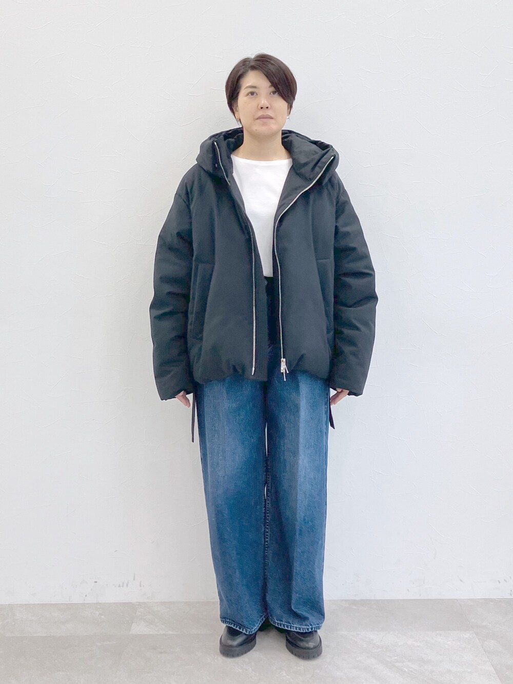 ブラック系のダウンジャケット/コート、ホワイト系のTシャツ/カットソー、ブルー系のデニムパンツを着用したレディースの秋コーディネートの5枚目の写真