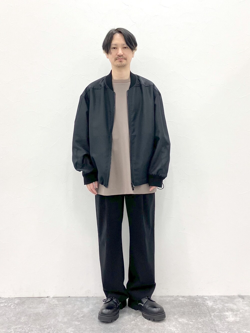 ブラック系のMA-1、ブラウン系のTシャツ/カットソー、ブラック系のスラックスを着用したメンズの春コーディネートの7枚目の写真