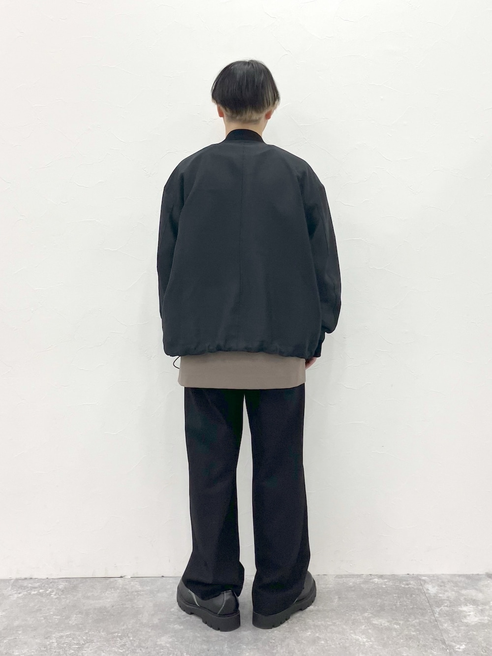 ブラック系のMA-1、ブラウン系のTシャツ/カットソー、ブラック系のスラックスを着用したメンズの春コーディネートの9枚目の写真