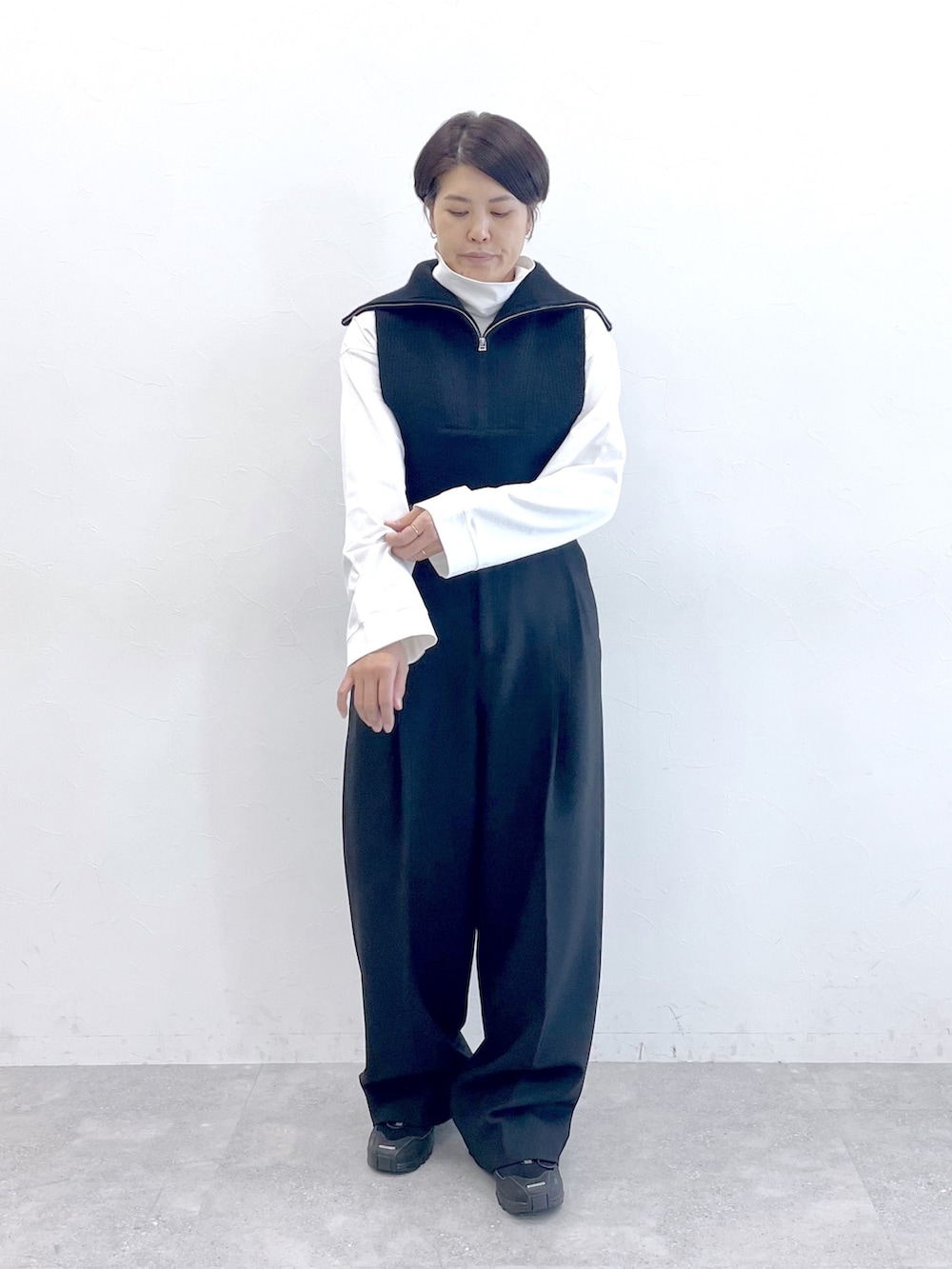 ブラック系のベスト、ホワイト系のTシャツ/カットソー、ブラック系のスラックスを着用したレディースの冬コーディネートの2枚目の写真