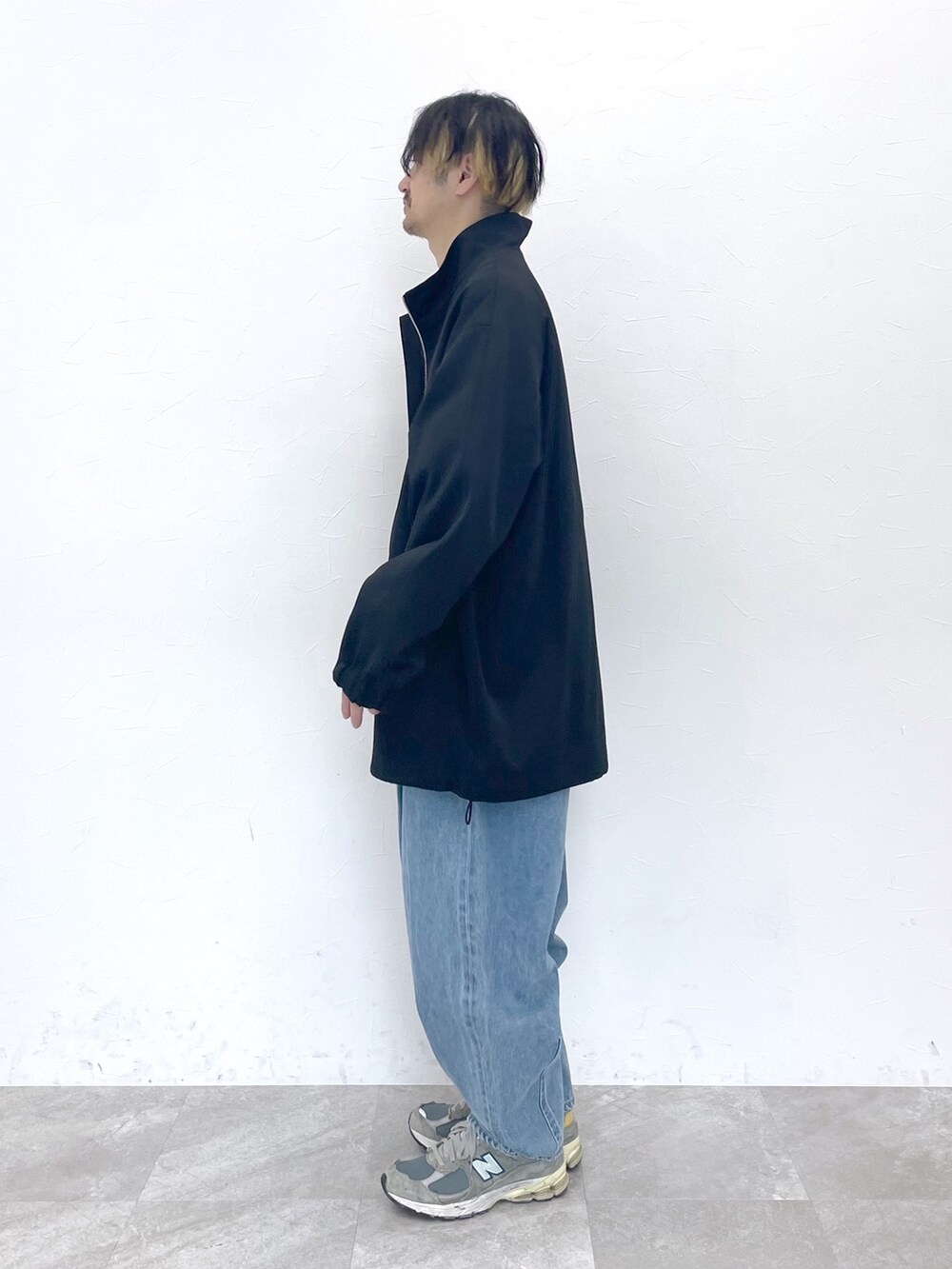 ブラック系のブルゾン、ベージュ系のトップス、ブルー系のデニムパンツを着用したメンズの冬コーディネートの7枚目の写真
