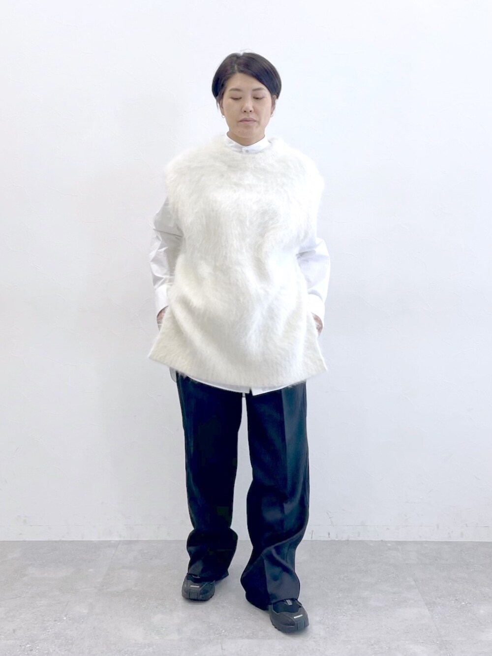 ホワイト系のニット/セーター、ホワイト系のシャツ/ブラウス、ブラック系のスラックスを着用したレディースの冬コーディネートの2枚目の写真