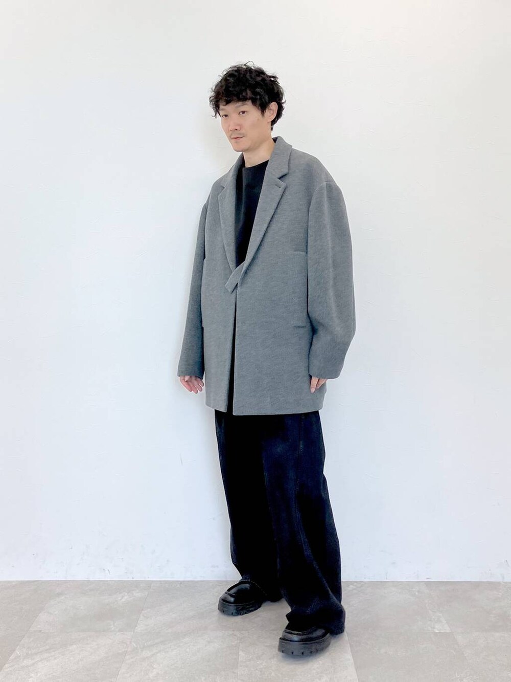 グレー系のステンカラーコート、ブラック系のデニムパンツ、ブラック系のデニムパンツを着用したメンズの秋コーディネートの2枚目の写真