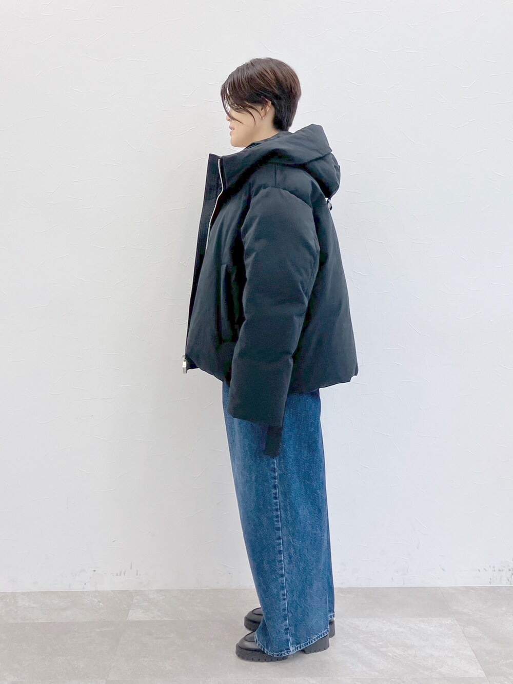 ブラック系のダウンジャケット/コート、ホワイト系のTシャツ/カットソー、ブルー系のデニムパンツを着用したレディースの秋コーディネートの6枚目の写真