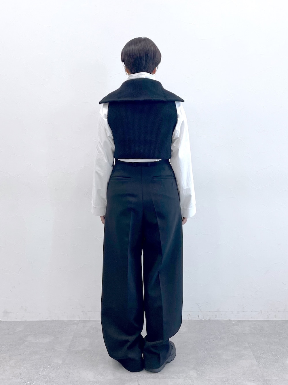 ブラック系のベスト、ホワイト系のTシャツ/カットソー、ブラック系のスラックスを着用したレディースの冬コーディネートの7枚目の写真