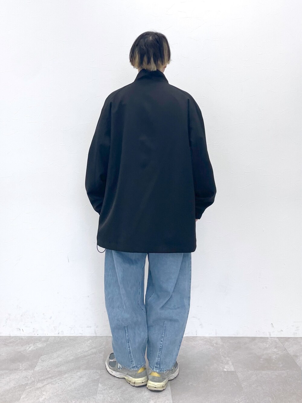 ブラック系のブルゾン、ベージュ系のトップス、ブルー系のデニムパンツを着用したメンズの冬コーディネートの2枚目の写真