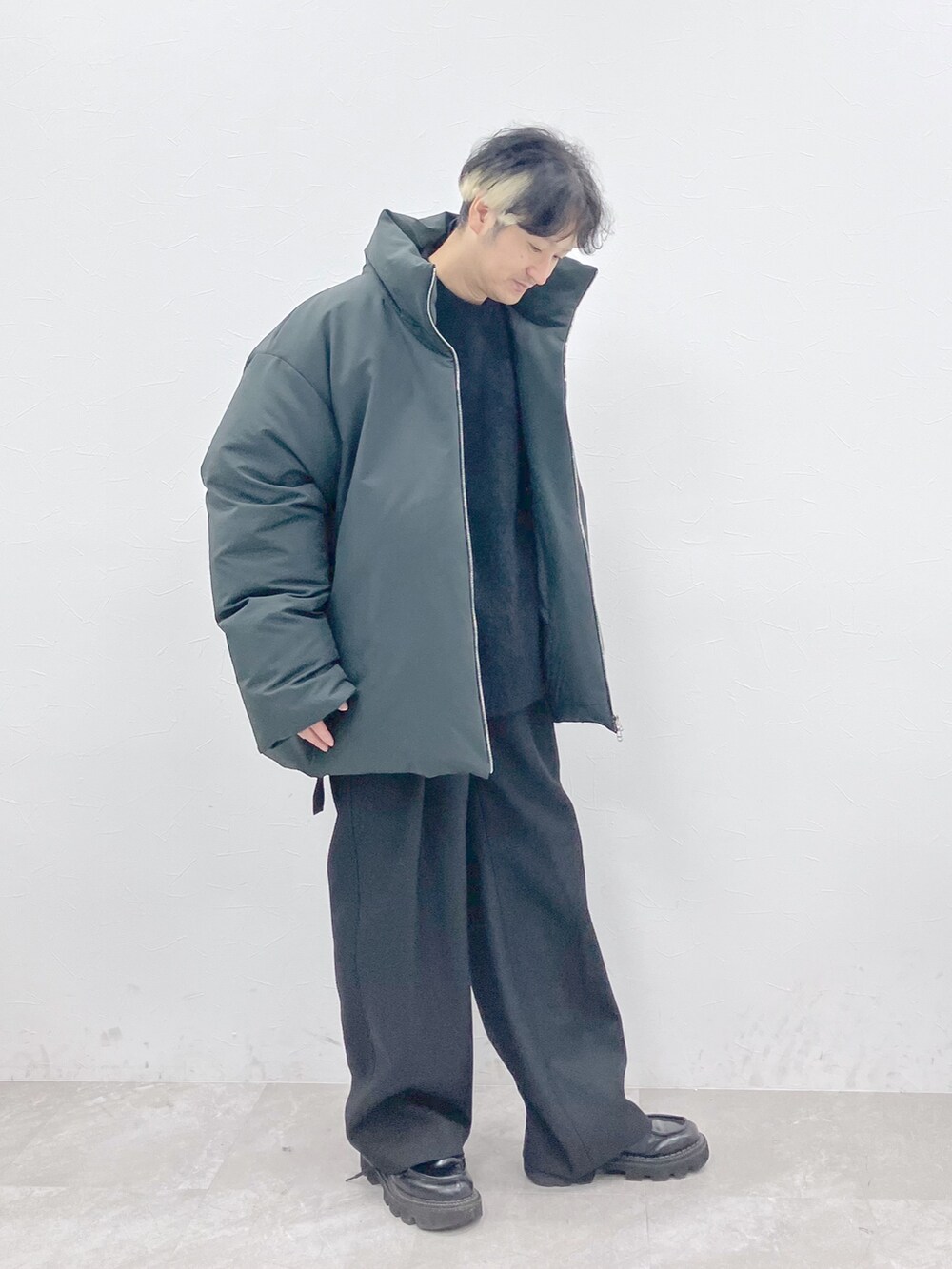 グレー系のダウンジャケット/コート、ブラック系のニット/セーター、ブラック系のその他パンツを着用したメンズの秋コーディネートの2枚目の写真
