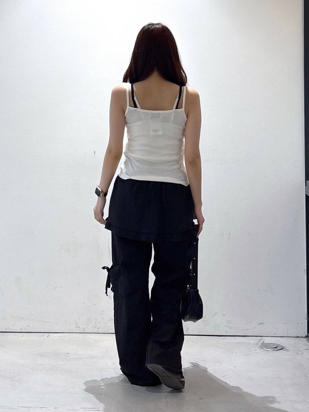 ブラック系のトートバッグ、ホワイト系のタンクトップ、ブラック系のカーゴパンツを着用したレディースの夏コーディネートの4枚目の写真