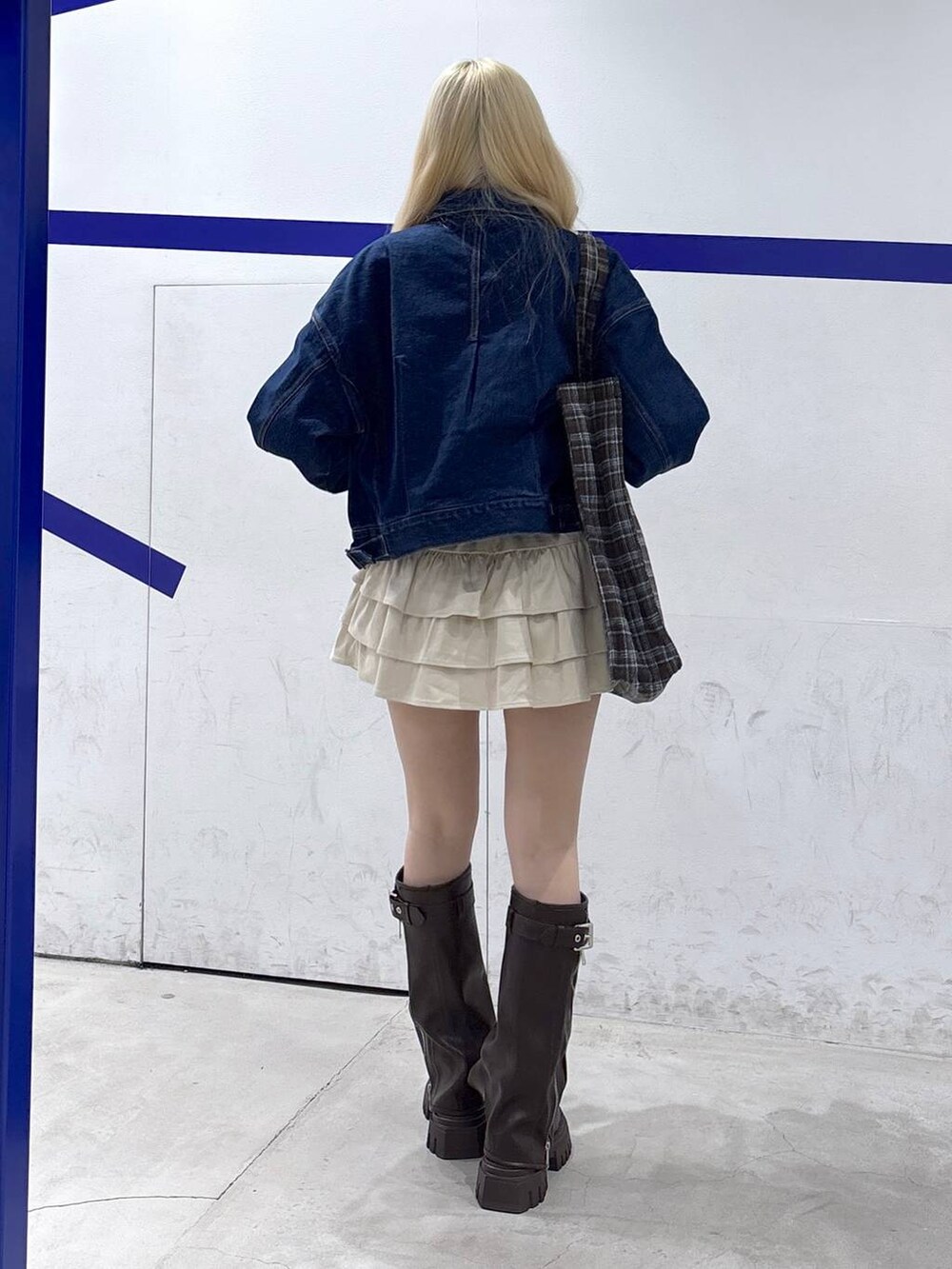 ブラウン系のトートバッグ、ブラウン系のブーツ、ブルー系のデニムジャケットを着用したレディースの秋コーディネートの5枚目の写真