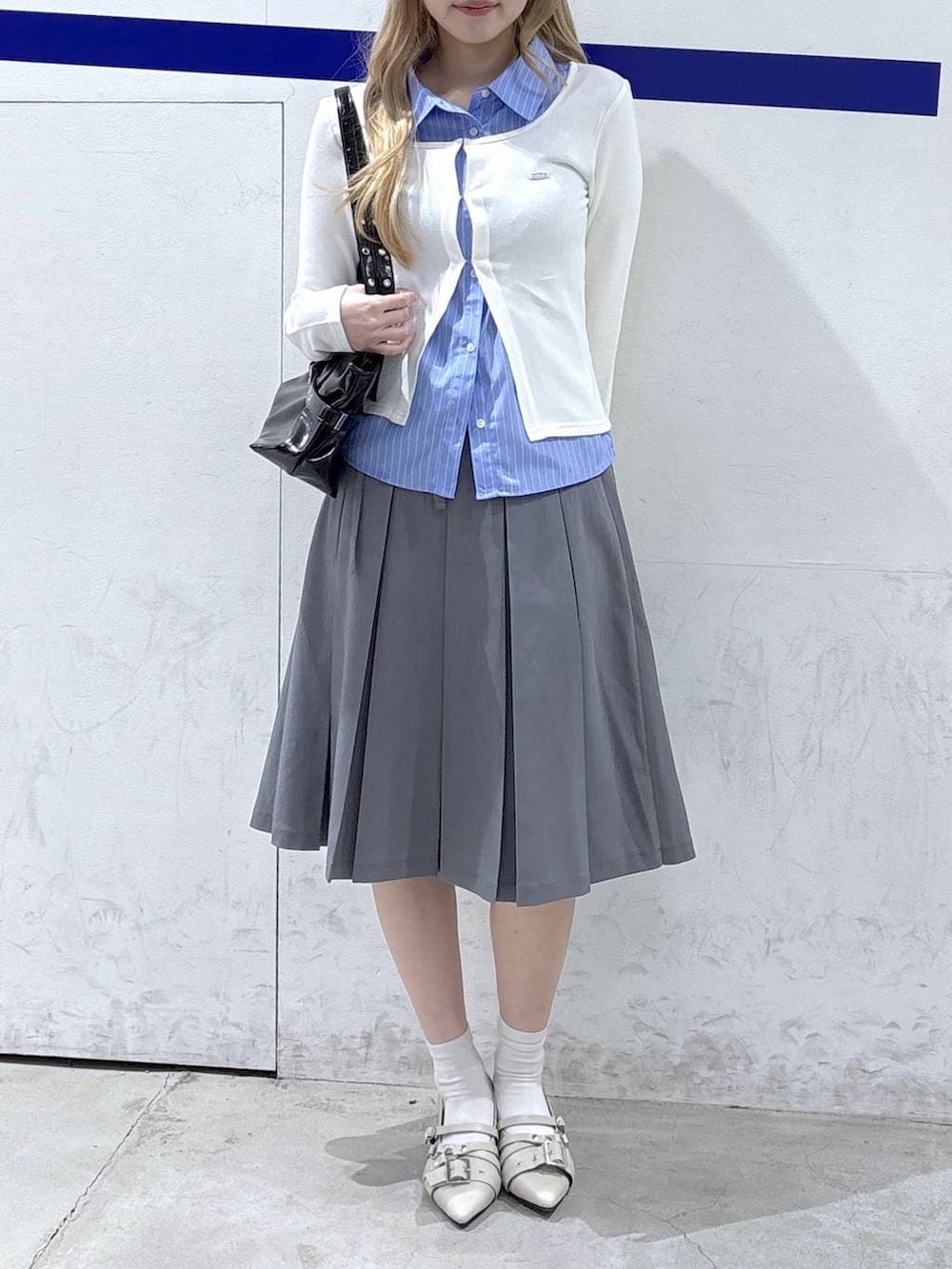 ホワイト系のパンプス、ブラック系のショルダーバッグ、ベージュ系のカーディガン/ボレロを着用したレディースの冬コーディネートの2枚目の写真