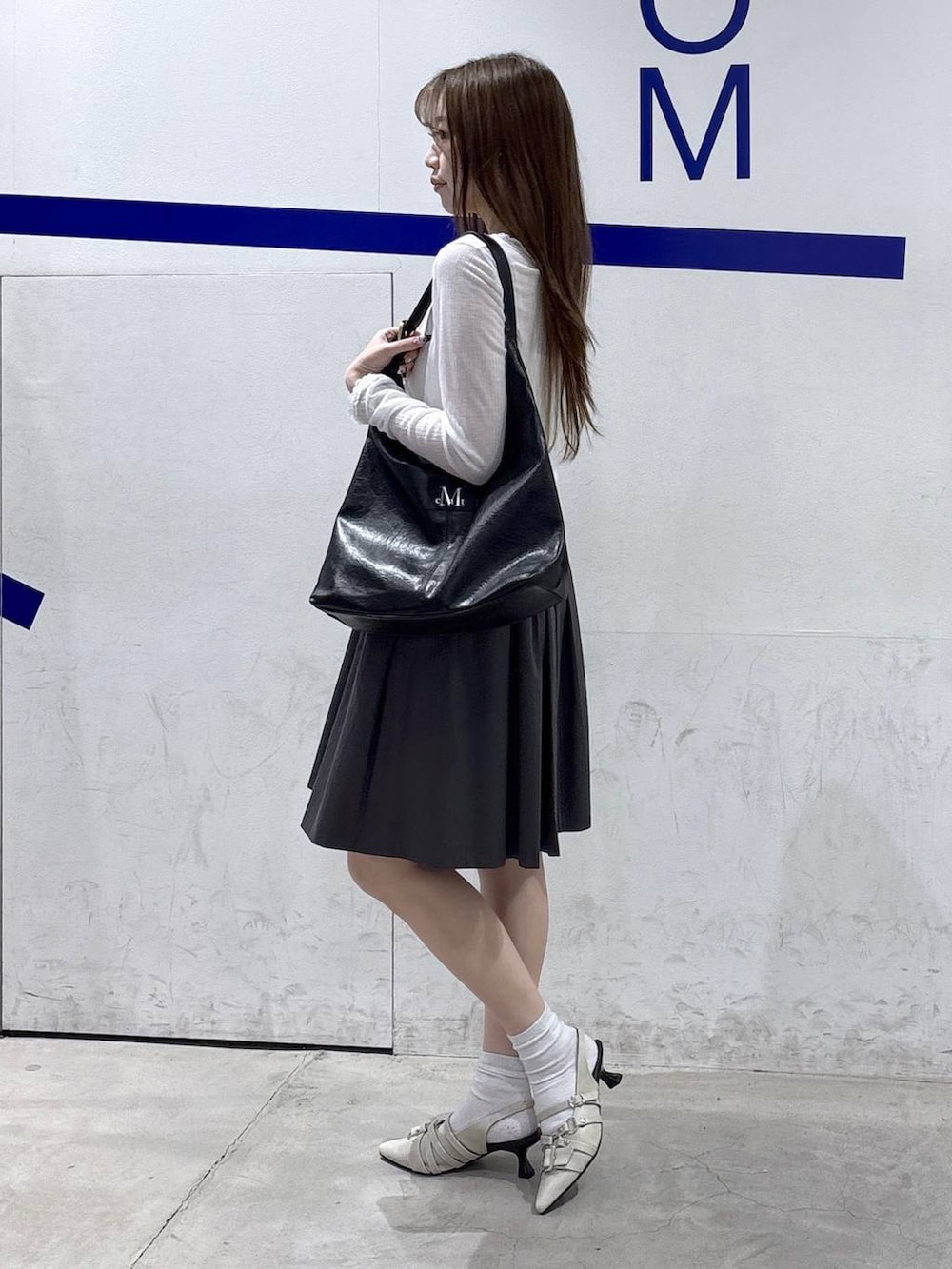 ホワイト系のパンプス、ブラック系のショルダーバッグ、グレー系のスカートを着用したレディースの春コーディネートの3枚目の写真