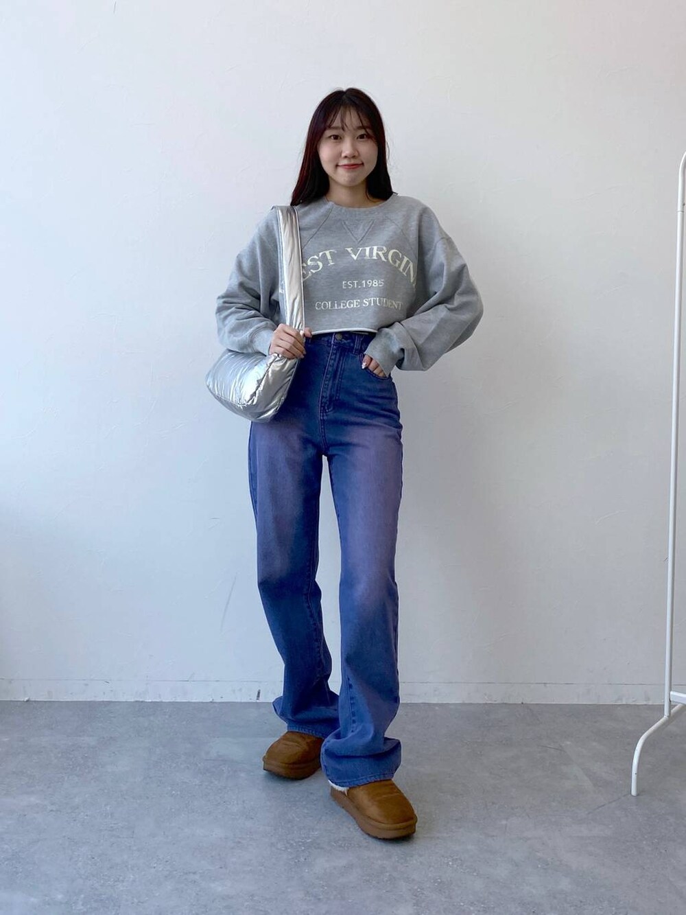 パープル系のデニムパンツ、その他のショルダーバッグ、グレー系のTシャツ/カットソーを着用したレディースの冬コーディネートの2枚目の写真