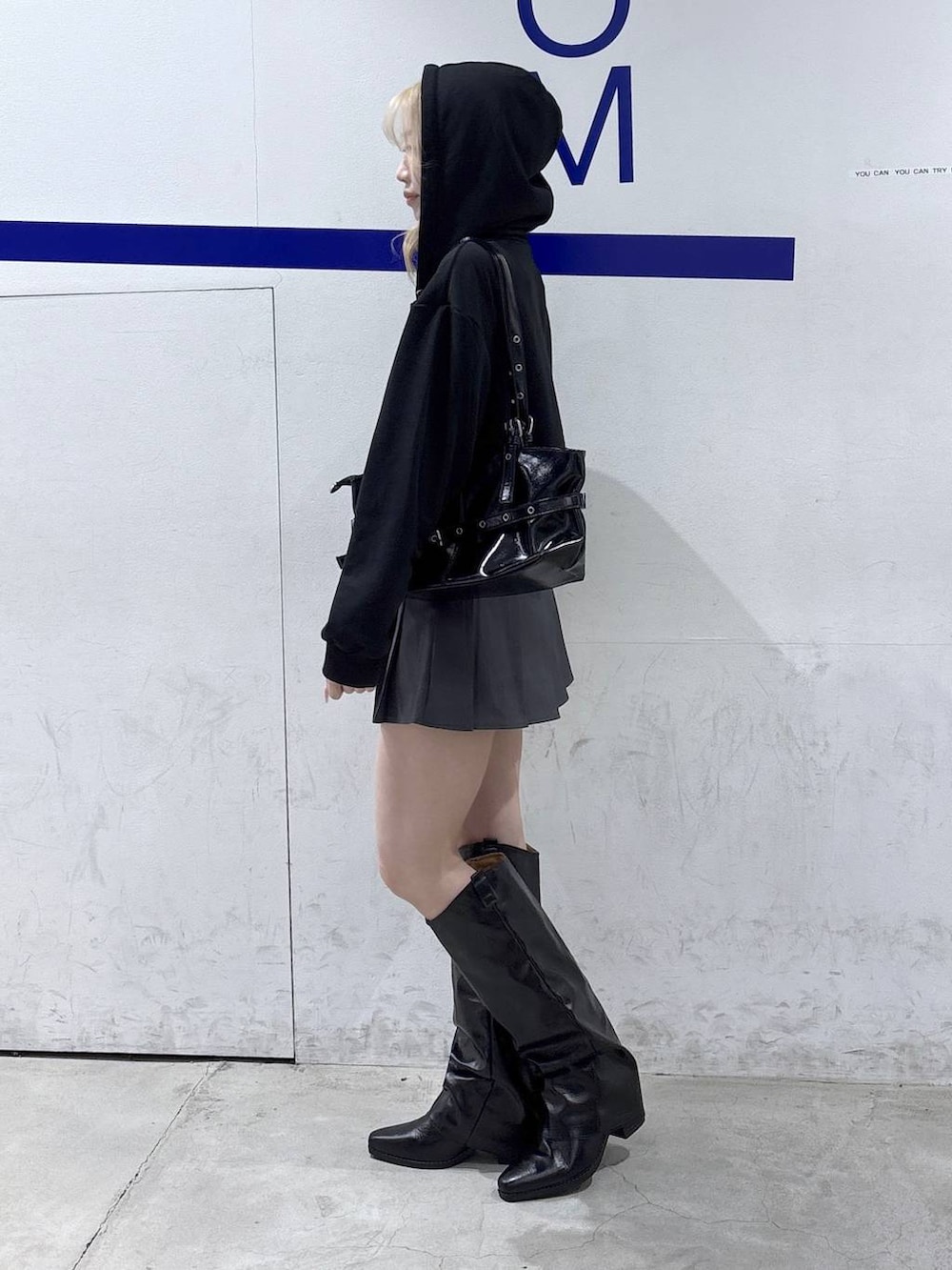 ブラック系のパーカー、ブラック系のブーツ、ブラック系のショルダーバッグを着用したレディースの冬コーディネートの3枚目の写真