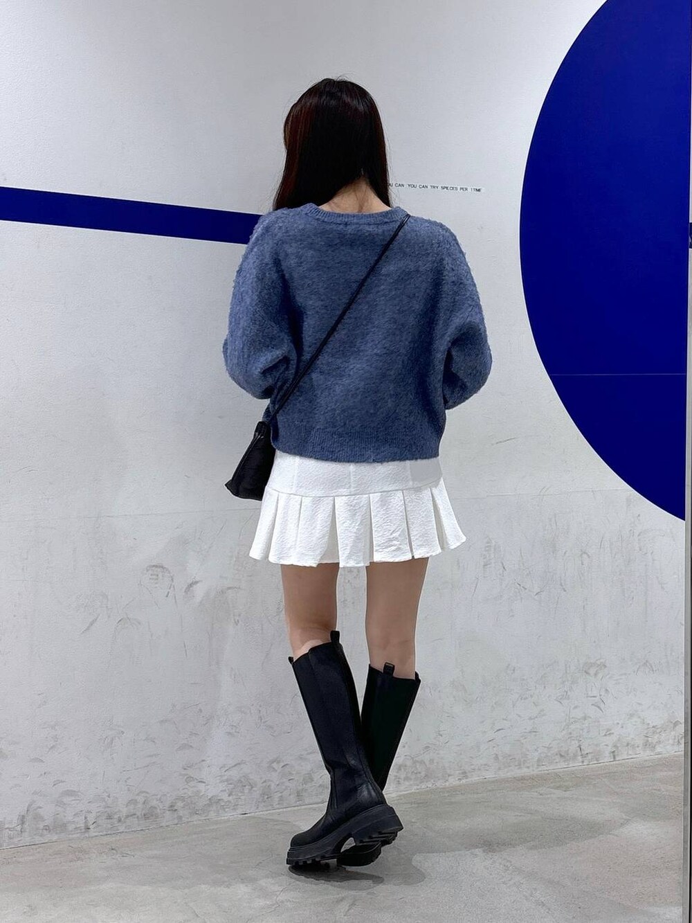 ホワイト系のスカート、ブラック系のブーツ、ブラック系のショルダーバッグを着用したレディースの秋コーディネートの4枚目の写真