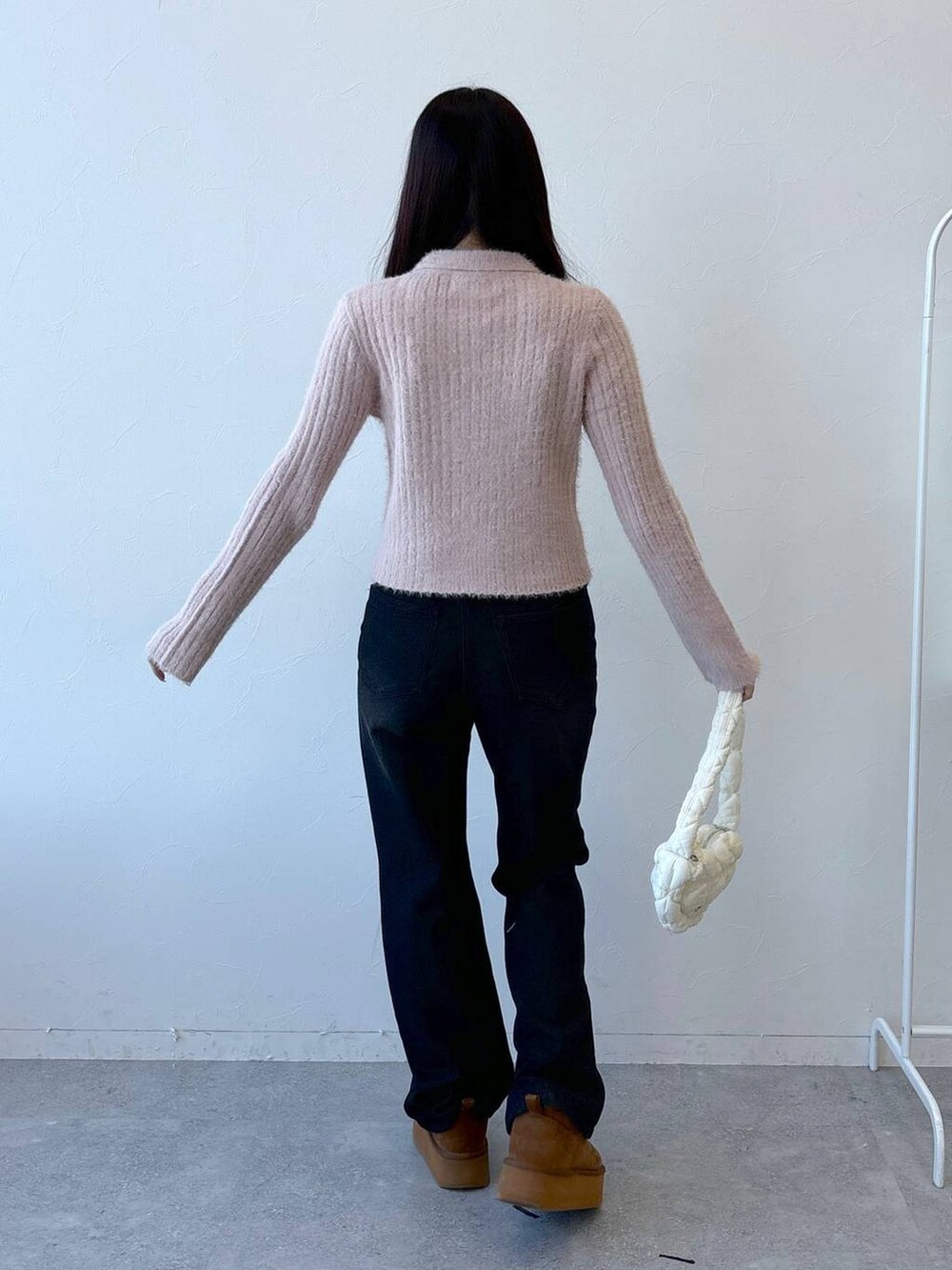 ホワイト系のショルダーバッグ、ブラック系のデニムパンツ、ピンク系のニット/セーターを着用したレディースの冬コーディネートの4枚目の写真