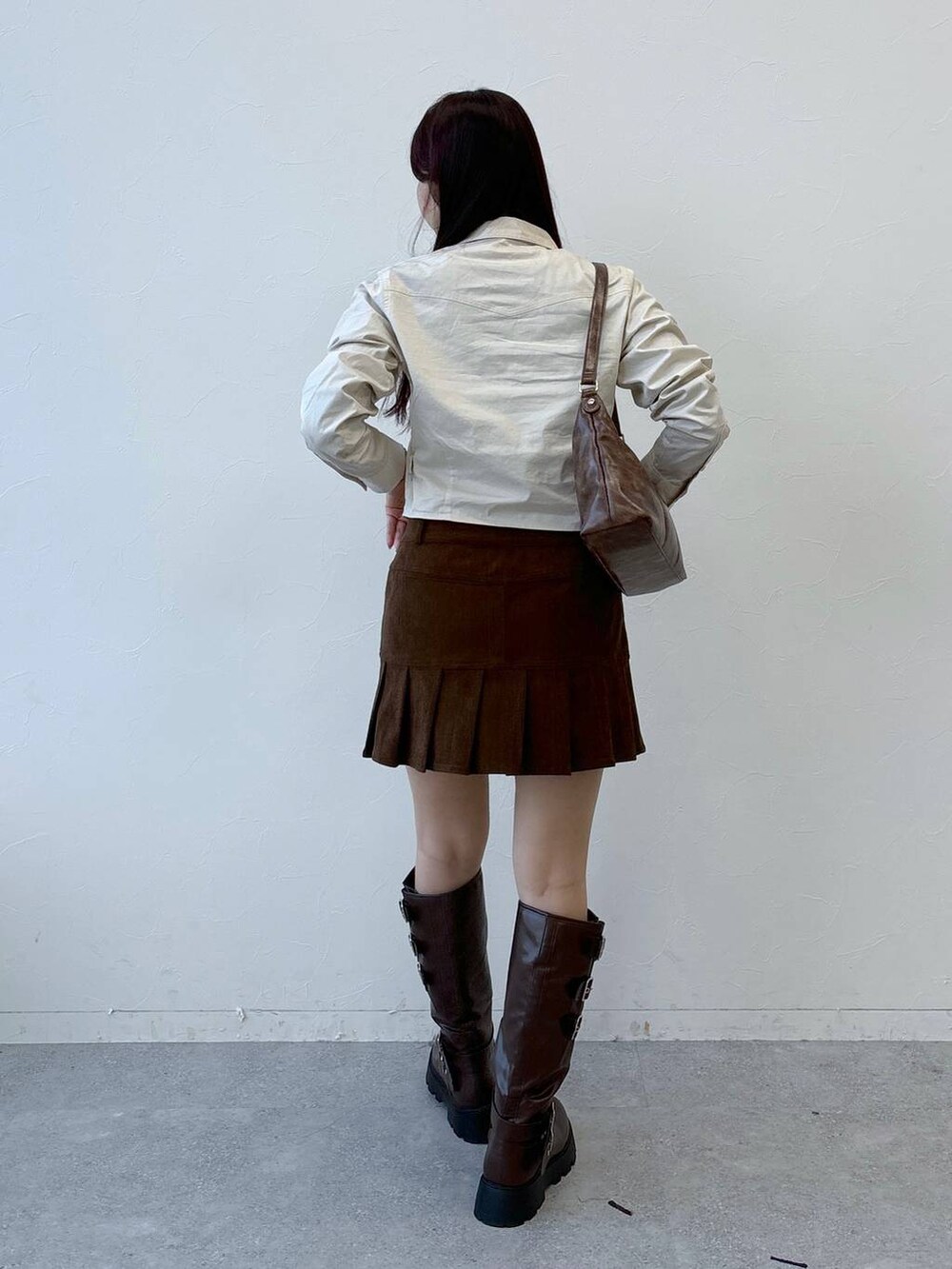 ブラウン系のブーツ、ブラウン系のスカート、ブラウン系のハンドバッグを着用したレディースの冬コーディネートの4枚目の写真