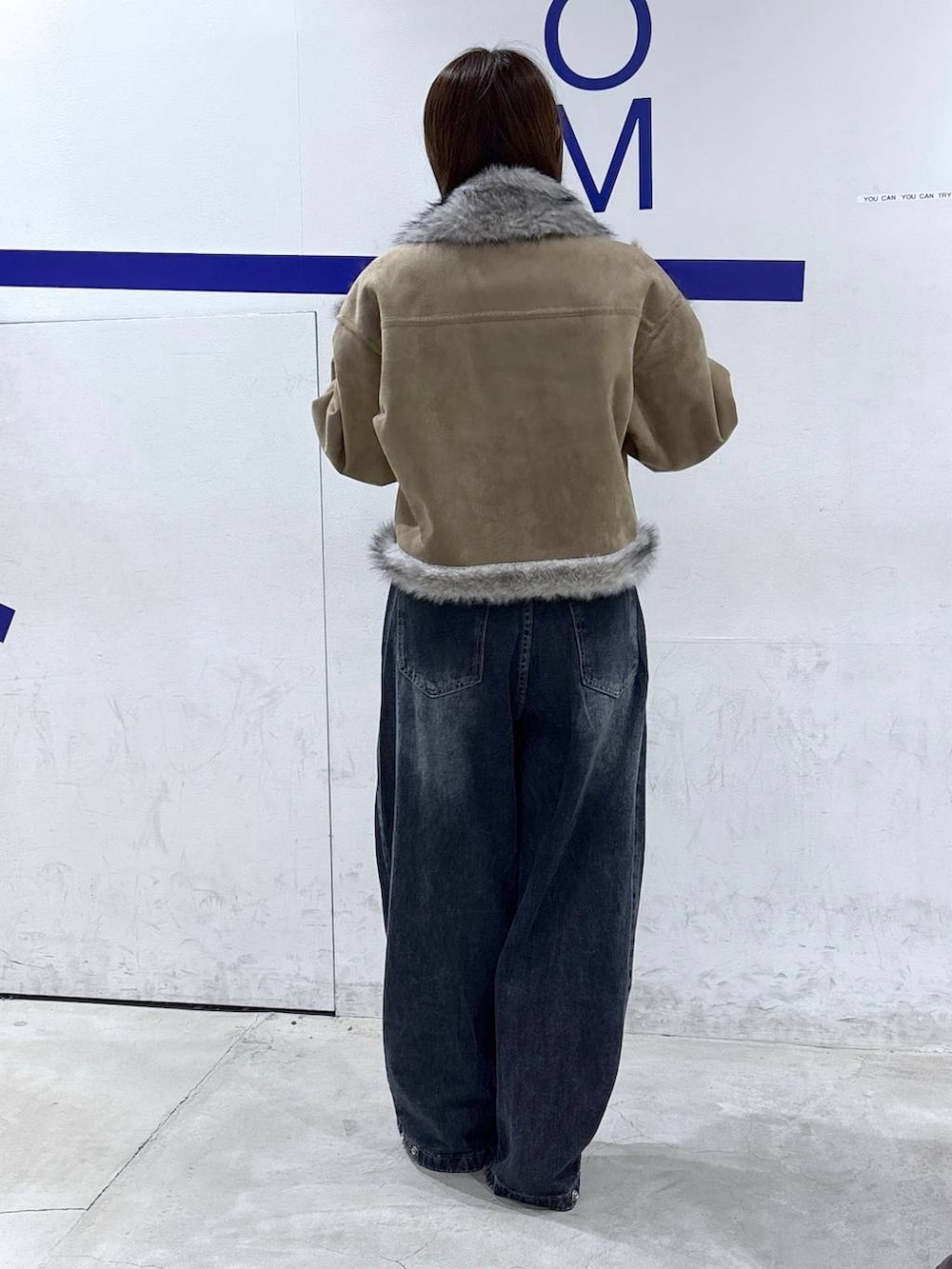 レッド系のTシャツ/カットソー、ブルー系のデニムパンツ、グレー系のムートンコートを着用したレディースの秋コーディネートの4枚目の写真