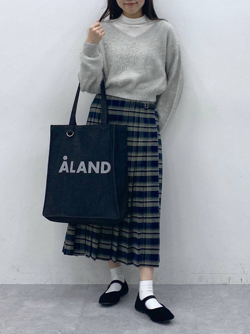 ブラック系のパンプス、ベージュ系のTシャツ/カットソー、ブルー系のスカートを着用したレディースの冬コーディネートの2枚目の写真