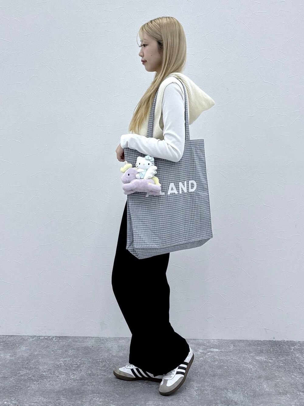 グレー系のトートバッグ、ホワイト系のベストを着用したレディースの冬コーディネートの3枚目の写真