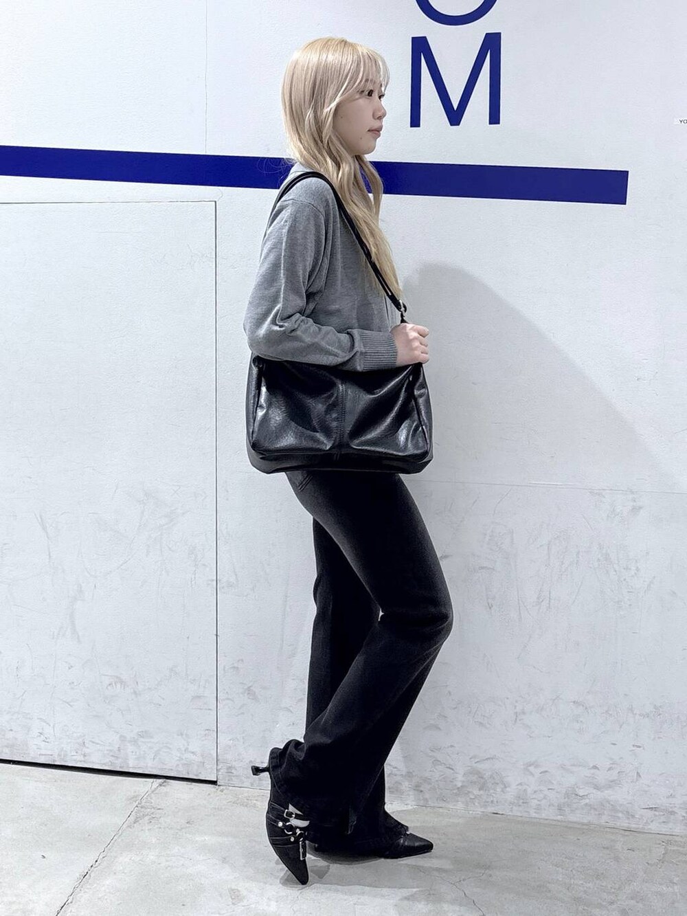 ブラック系のショルダーバッグ、ブラック系のデニムパンツ、ブラック系のパンプスを着用したレディースの冬コーディネートの5枚目の写真