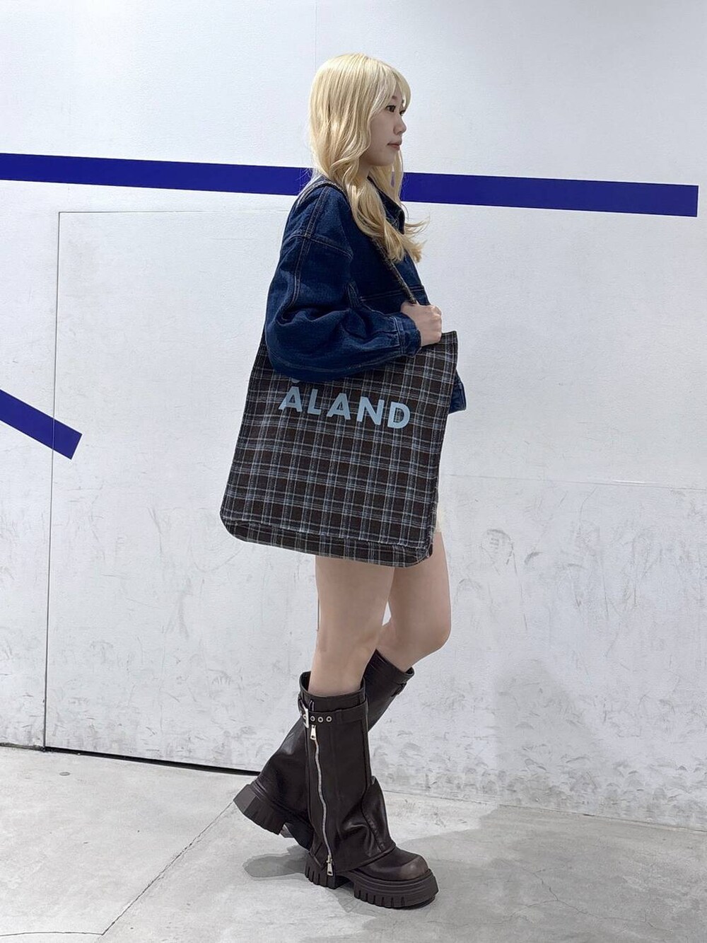 ブラウン系のトートバッグ、ブラウン系のブーツ、ブルー系のデニムジャケットを着用したレディースの秋コーディネートの3枚目の写真