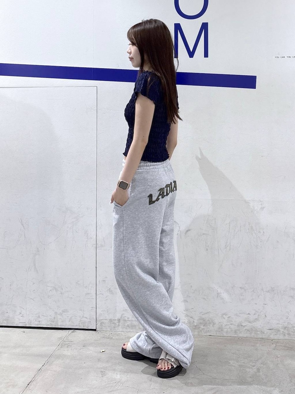 ホワイト系のサンダル、ブルー系のTシャツ/カットソー、グレー系のスウェットパンツを着用したレディースの夏コーディネートの3枚目の写真