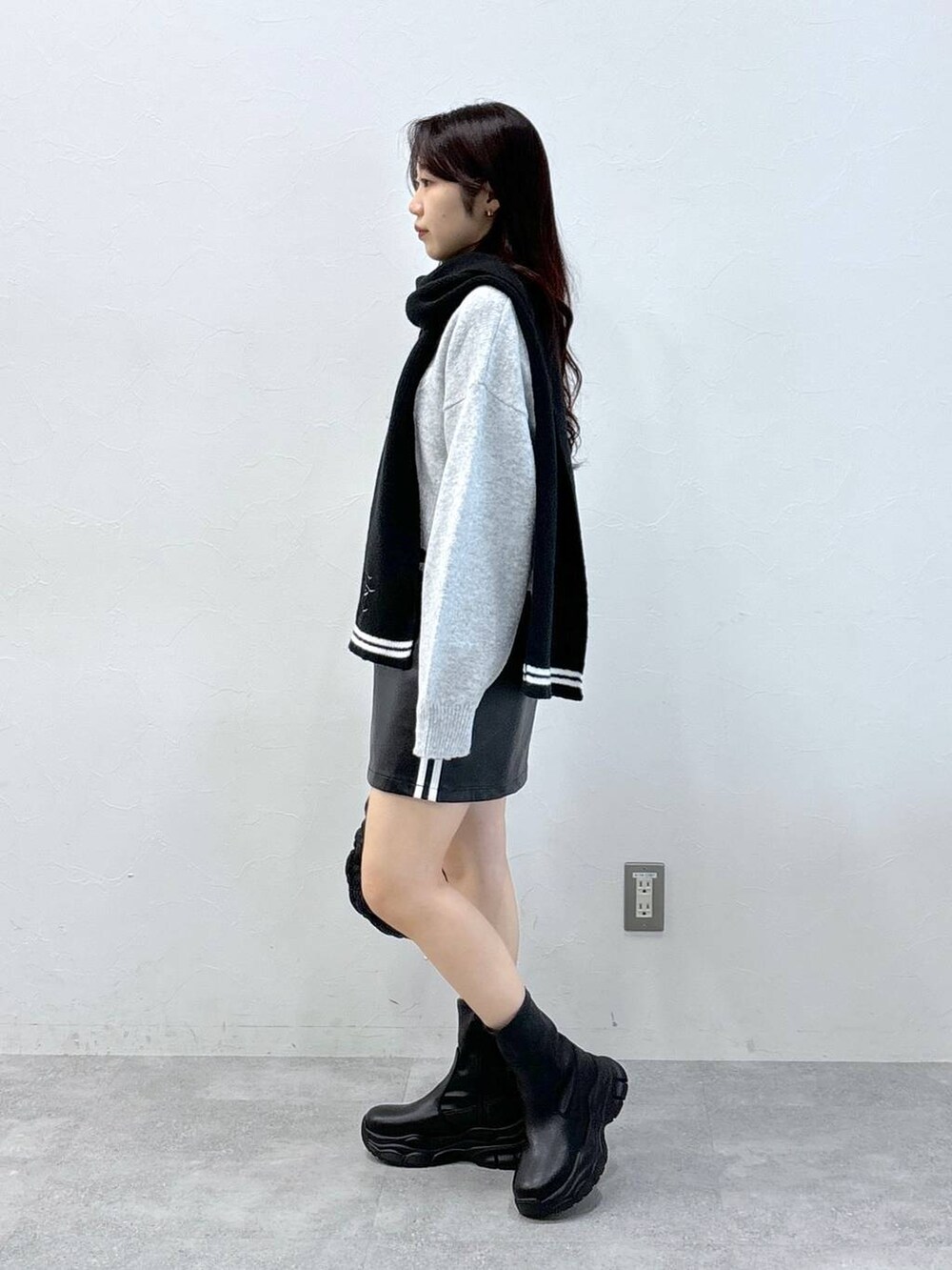 ブラック系のショルダーバッグ、グレー系のニット/セーター、ブラック系のスカートを着用したレディースの秋コーディネートの4枚目の写真