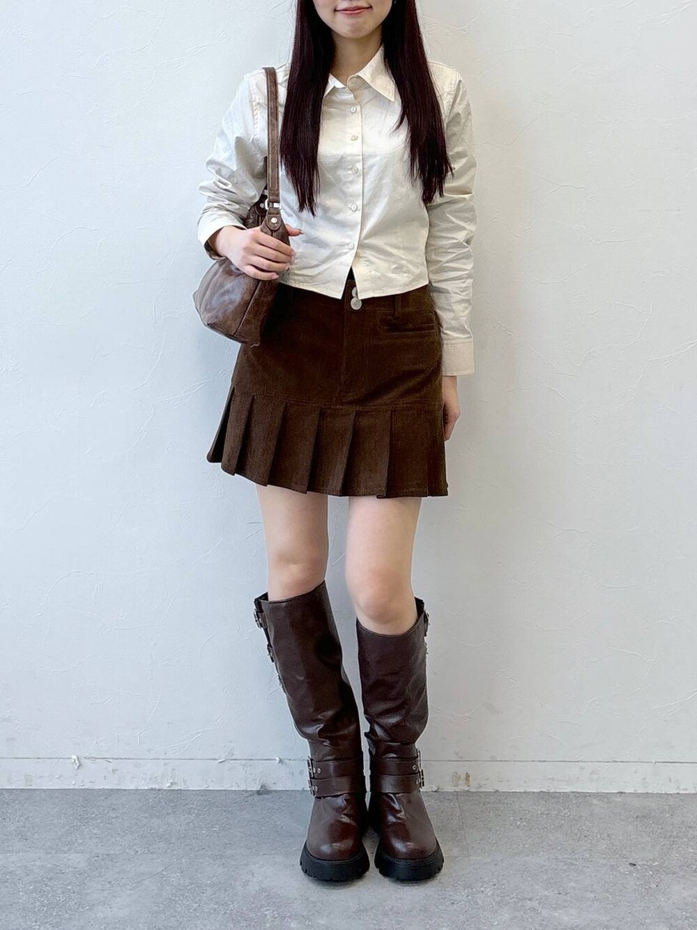 ブラウン系のブーツ、ブラウン系のスカート、ブラウン系のハンドバッグを着用したレディースの冬コーディネートの2枚目の写真