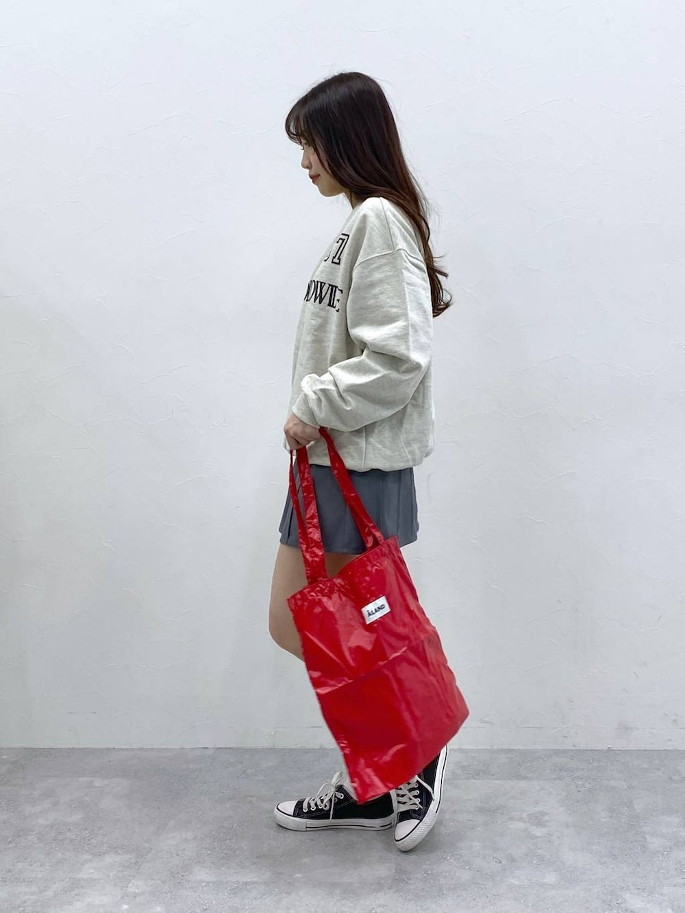 グレー系のスカート、レッド系のトートバッグ、ベージュ系のスウェットを着用したレディースの春コーディネートの3枚目の写真