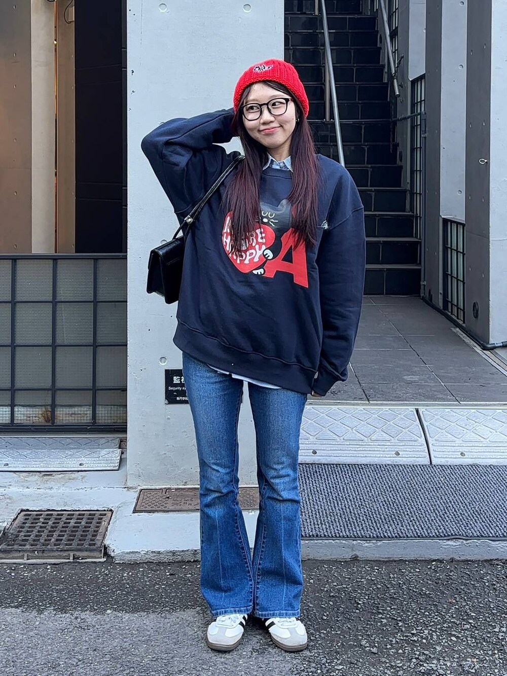 ブルー系のデニムパンツ、ブラック系のショルダーバッグ、ブルー系のスウェットを着用したレディースの冬コーディネートの2枚目の写真