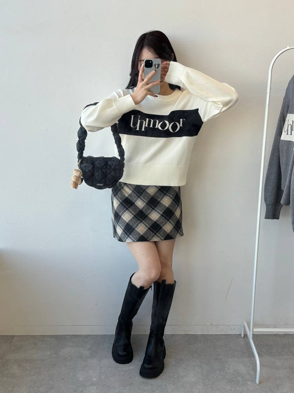 ブラック系のショルダーバッグ、ブラック系のスカート、ブラック系のブーツを着用したレディースの冬コーディネートの5枚目の写真