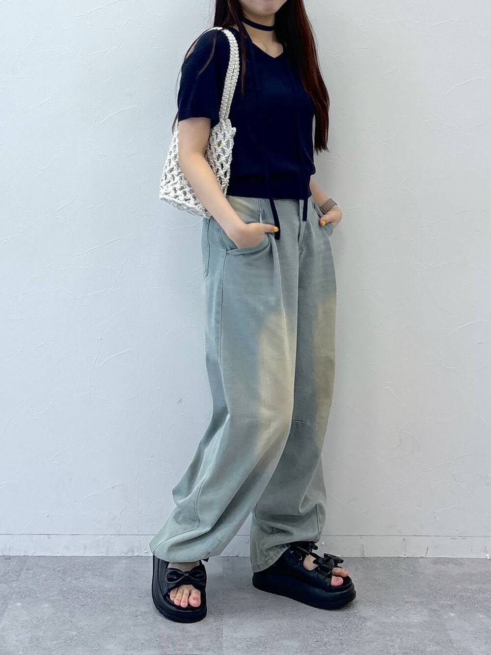 ブルー系のデニムパンツ、ブラック系のサンダル、ベージュ系のトートバッグを着用したレディースの夏コーディネートの3枚目の写真