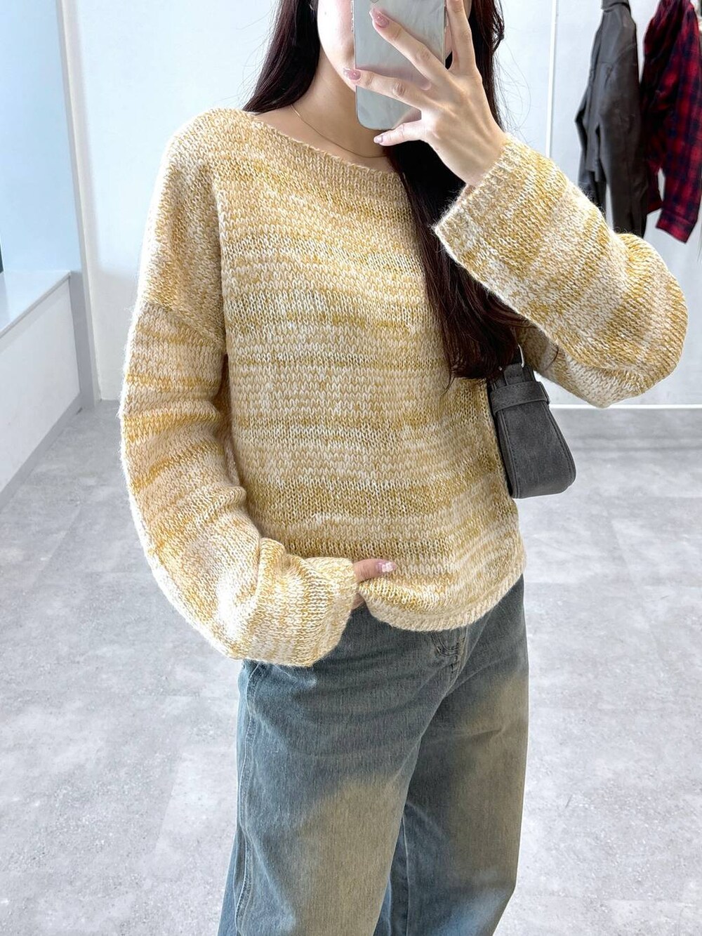 ブラック系のトートバッグ、ブルー系のデニムパンツ、ベージュ系のニット/セーターを着用したレディースの秋コーディネートの5枚目の写真